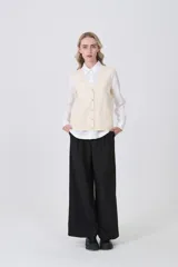 Chaleco de punto gris con escote en V, cierre frontal de botones y dos bolsillos delanteros con terminación acanalada.