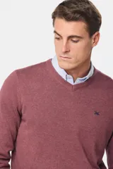 Suéter de tejido fino color azul marino, con cuello en V y manga larga. Presenta un pequeño logo bordado en el pecho.