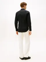 Camisa de manga larga para hombre, color negro liso, con cuello con botones y corte slim. Presenta un pequeño logo bordado de la marca en el pecho.