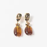 Caravanas colgantes con base metálica dorada de forma irregular y dije de piedra ámbar en tono marrón translúcido.