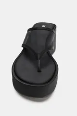Sandalias negras con tacón de cuña alta y acabado satinado. Presenta una tira de dedo y empeine confeccionadas en tejido mesh translúcido y diseño de punta redonda.