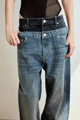 Jeans de tiro bajo confeccionados en denim, con diseño holgado y bajo con vuelta. Presentan el detalle de doble cinturilla en tonos contrastantes de azul, cierre frontal con cremallera y botón metálico, y cinco bolsillos clásicos.