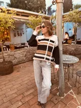 Sweater de punto con diseño a rayas horizontales en tonos blanco, negro, marrón y rosa.