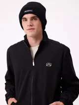 Gorro tipo beanie de tejido acanalado en color negro, con parche rectangular con el logo de la marca en el frente.