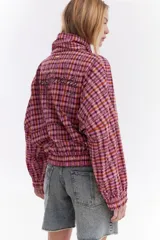 Chaqueta bomber de algodón con estampado a cuadros en tonos azules, amarillos y marrones, cuello alto y cierre frontal descentrado con botones. Cuenta con mangas abullonadas y puños elásticos.