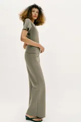 Pantalón largo negro de tiro alto, confeccionado en tejido elástico, con cintura elástica y diseño de pierna ancha tipo palazzo con bajo evasé.