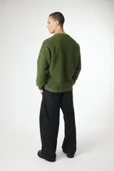 Buzo de cuello redondo confeccionado en tejido tipo polar de color negro. Presenta un diseño de mangas raglán y un bolsillo de parche en el pecho en tela técnica contrastante con cierre de cremallera vertical y etiqueta de la marca. Posee puños y cuello acanalados.