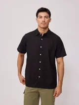 Camisa de manga corta color negro, con cuello clásico y cierre frontal de botones.