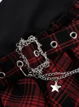 Minifalda asimétrica de cuadros tartán en rojo y negro, con detalles de encaje negro, una cadena metálica colgante y hebilla decorativa.