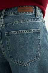 Jean de corte wide leg con diseño de costuras verticales decorativas en el frente, tiro medio y cierre frontal con botón y cremallera.