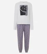 Pijama largo de dos piezas compuesto por una remera de manga larga color blanco con cuello redondo y estampa frontal de un gato con collar de perlas, y un pantalón color lila con estampado de lunares blancos, cintura elástica con cordón y puños ajustados en los tobillos.