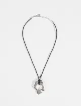 Collar de cordón negro con dije metálico en forma de flor irregular de acabado plateado. Incluye cadena de alargue metálica con cierre de mosquetón.
