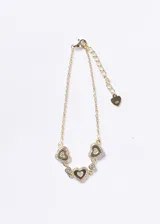 Pulsera de cadena fina con tres dijes en forma de corazón y dos puntos de luz intercalados. Los corazones están decorados con pavé de zirconias. Incluye cadena de extensión con un pequeño dije de corazón al final.