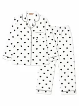 Camisa de pijama de manga larga con cuello solapa, cierre frontal de botones y bolsillo en el pecho. Presenta un estampado de corazones negros sobre fondo blanco y detalles de ribetes negros en cuello, puños y bolsillo.