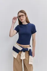 Top de manga corta color beige, confeccionado en tejido elastizado con textura acanalada, cuello redondo y calce al cuerpo.