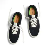 Championes de skate negros de lona con cordones blancos y suela de goma blanca.