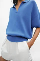 Polo amplio de punto color celeste, con cuello y escote en V, de manga corta.