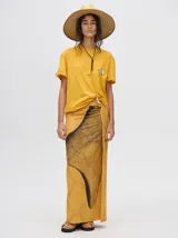 Pareo largo de viscosa en color mostaza, con diseño gráfico central en color negro que simula una textura de puntos. Es una prenda liviana y fresca, ideal para usar sobre el traje de baño o como falda casual.