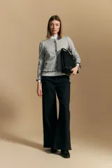 Cárdigan beige de manga larga, tejido liviano y suave, con volados en el delantero, ruedo y puños. Cierre frontal con botones.