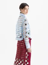 Camisa de manga larga confeccionada en guipur con apliques de espejos circulares. Presenta cuello clásico, puños y cartera de botones a presión forrados al tono. Incluye top interno al tono.