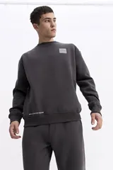 Buzo de algodón con calce oversize, cuello redondo, mangas largas con puños y bolsillos laterales. Presenta un parche cuadrado negro con lettering en el pecho y detalle de estampado en el ruedo.