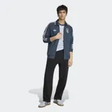 Campera deportiva Adidas de la selección de Italia, color azul con diseño retro. Presenta cuello tipo polo, cierre frontal completo, bolsillos laterales y las icónicas tres tiras de la marca en las mangas. Incluye el logo del Trifolio y el escudo de la Federación Italiana de Fútbol en el pecho.