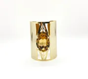 Brazalete dorado ancho de metal brillante con una piedra de cristal topacio ovalada engarzada en el centro. Es ajustable.