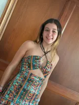 Vestido corto con estampado de rayas horizontales en tonos grises y negros. Diseño con escote halter que se ata al cuello, abertura central en el busto y falda corta con volado.