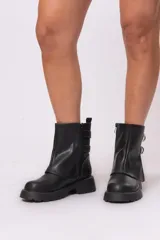 Botas biker cortas de cuero sintético negro, con suela track, cierre lateral con cremallera y doble hebilla decorativa.