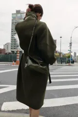 Bolso de mano de formato alargado con textura de efecto cocodrilo. Cuenta con asa de mano superior, asa extraíble para usar como bandolera, bolsillo interior con cierre y cierre frontal mediante clip metálico.