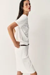 Camiseta blanca de algodón con cuello redondo, manga corta y detalle de flor en relieve bordada en el mismo tono.