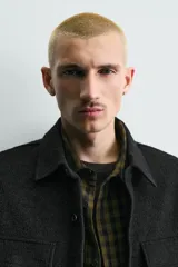 Sobrecamisa de corte relajado confeccionada en tejido de estructura irregular con lana. Presenta cuello solapa, cierre frontal con botones, mangas largas con puños abotonados y bolsillos frontales con solapa en el pecho.
