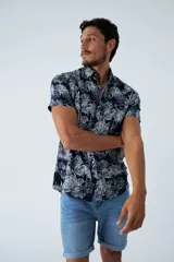 Camisa de manga corta con estampado botánico de hojas en tonos azul y blanco. Presenta cuello clásico, cierre frontal abotonado y corte slim.