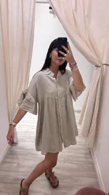 Vestido camisero corto color marrón, de lino italiano, con cuello camisero, cierre frontal con botones, doble volado en las mangas y bolsillos laterales.