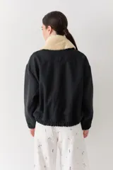 Campera bomber de paño color beige, con cierre frontal, cuello alto y puños elásticos.