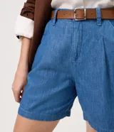 Short de sastrería confeccionado en jean azul de algodón, con cintura alta, pinzas delanteras, bolsillos laterales y presillas. Incluye un cinturón delgado de cuero marrón con hebilla metálica.