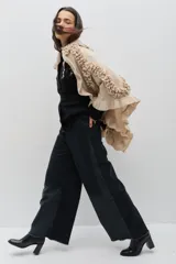 Chal de lana color marrón con diseño envolvente, decorado con volados aplicados en toda la superficie que aportan textura y movimiento.