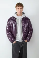 Campera acolchada de acabado brillante en color violeta oscuro, con cuello alto y cierre frontal con cremallera.