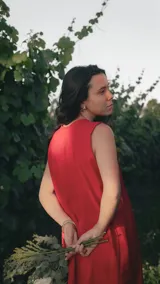 Vestido corto sin mangas de color rojo, con escote en V y detalle de alforzas verticales en el frente. Presenta un diseño de silueta relajada y fluida.