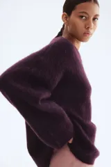 Buzo de punto oversized color morado oscuro, con textura suave y peluda, cuello redondo y hombros caídos.