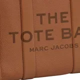 Bolso tipo tote de gran tamaño, confeccionado en cuero negro con textura granulada. Presenta el logo de la marca estampado en el frente con la inscripción The Tote Bag Marc Jacobs. Cuenta con asas superiores resistentes y un diseño espacioso.
