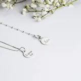 Conjunto de cadena fina y medalla circular de plata 925, con grabado lineal de figuras infantiles en el frente.