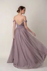 Vestido largo de fiesta color lila, confeccionado en gasa. Presenta un corsé drapeado con escote off-shoulder y mangas caídas. La falda es amplia y fluida.