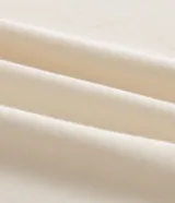 Blusa de corte boxy en color crudo, con cuello redondo y mangas cortas estilo godê. Presenta detalles de bordado floral en tonos marrones en ambas mangas.