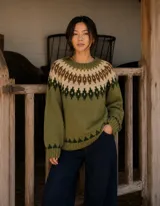 Buzo de lana merino con diseño tejido de inspiración nórdica, presenta un patrón geométrico en el canesú y en el ruedo en tonos oliva, crudo y chocolate. Posee cuello redondo, mangas largas y puños acanalados.