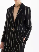 Blazer de jacquard negro con rayas verticales formadas por pequeños estampados de labios. Presenta solapas con vivo, bolsillo relojero y cierre frontal con broche snap dorado.