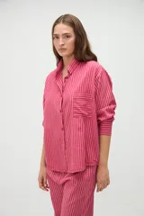 Camisa de manga larga de algodón, con diseño a rayas en tonos azules y morados, calce holgado, cuello camisero, cierre frontal con botones y un bolsillo aplicado en el pecho.