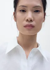 Camisa de manga corta con cuello camisero y cierre frontal de botones. Confeccionada en una mezcla de lino y algodón, presenta un diseño recto y minimalista.