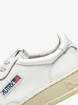 Championes Autry Medalist Low de cuero blanco con detalles en azul y rojo. Suela color crema y logo de la marca en el lateral. Diseño de estilo retro.