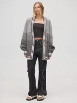 Cardigan oversize de algodón con diseño tejido a rombos en tonos degradados de marrón y blanco. Presenta cuello en V, cierre frontal con botones de madera y puños y dobladillo con rayas blancas.